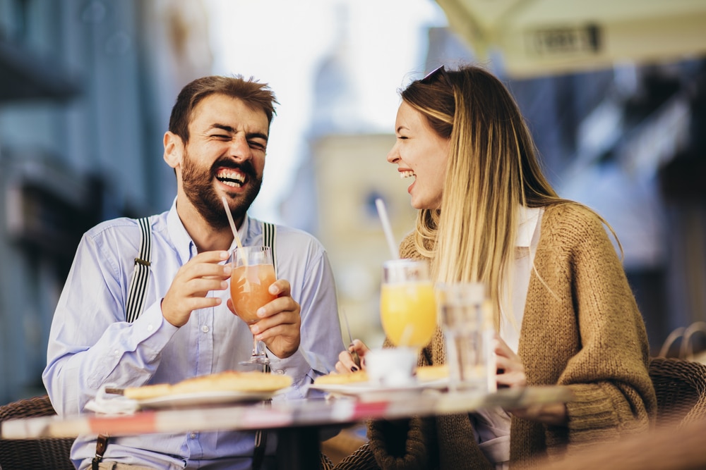 Young couple sitting in a restaurant eating pizza outdoor.